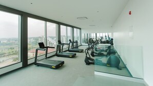Een moderne sportschool met loopbanden en fitnessapparatuur, grote ramen met uitzicht over de stad.