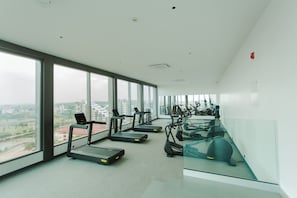 A modern gym with treadmills and exercise equipment, large windows offering city views. - A Plush Studio at Loxwood House (Accra)