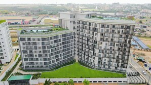 Un immeuble résidentiel de grande hauteur doté de nombreux balcons, d’une cour intérieure et d’un jardin sur le toit.