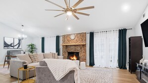 A modern living room with a fireplace, a sofa, a coffee table, and a TV. - Shadowlake 4BR House (Charlotte)