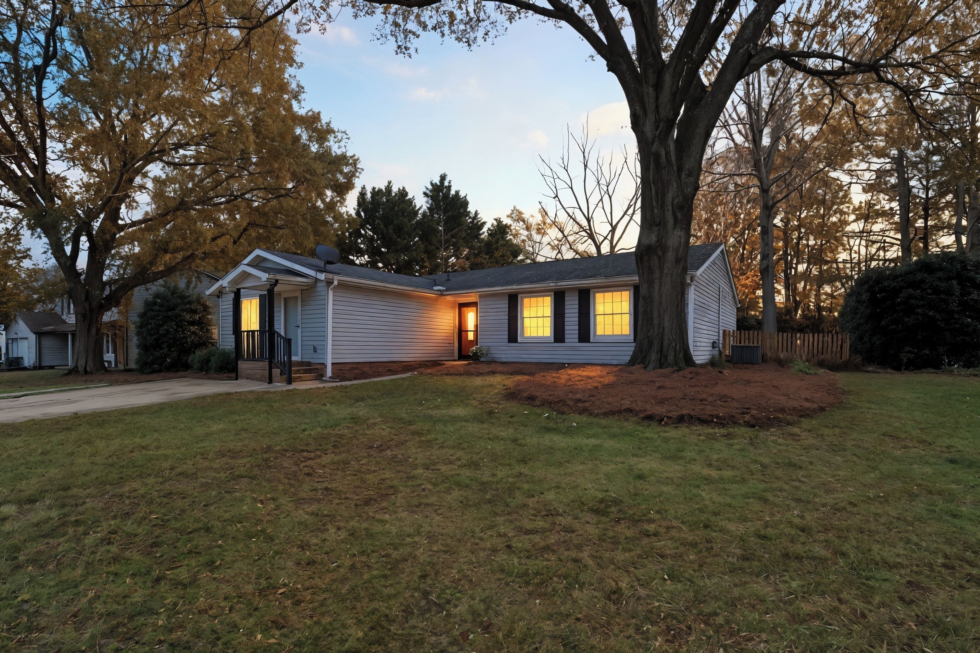 A single-story house with a front porch, a large tree in the yard, and a well-maintained lawn.