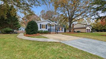 A two-story house with a front porch, a driveway, and a well-maintained lawn.