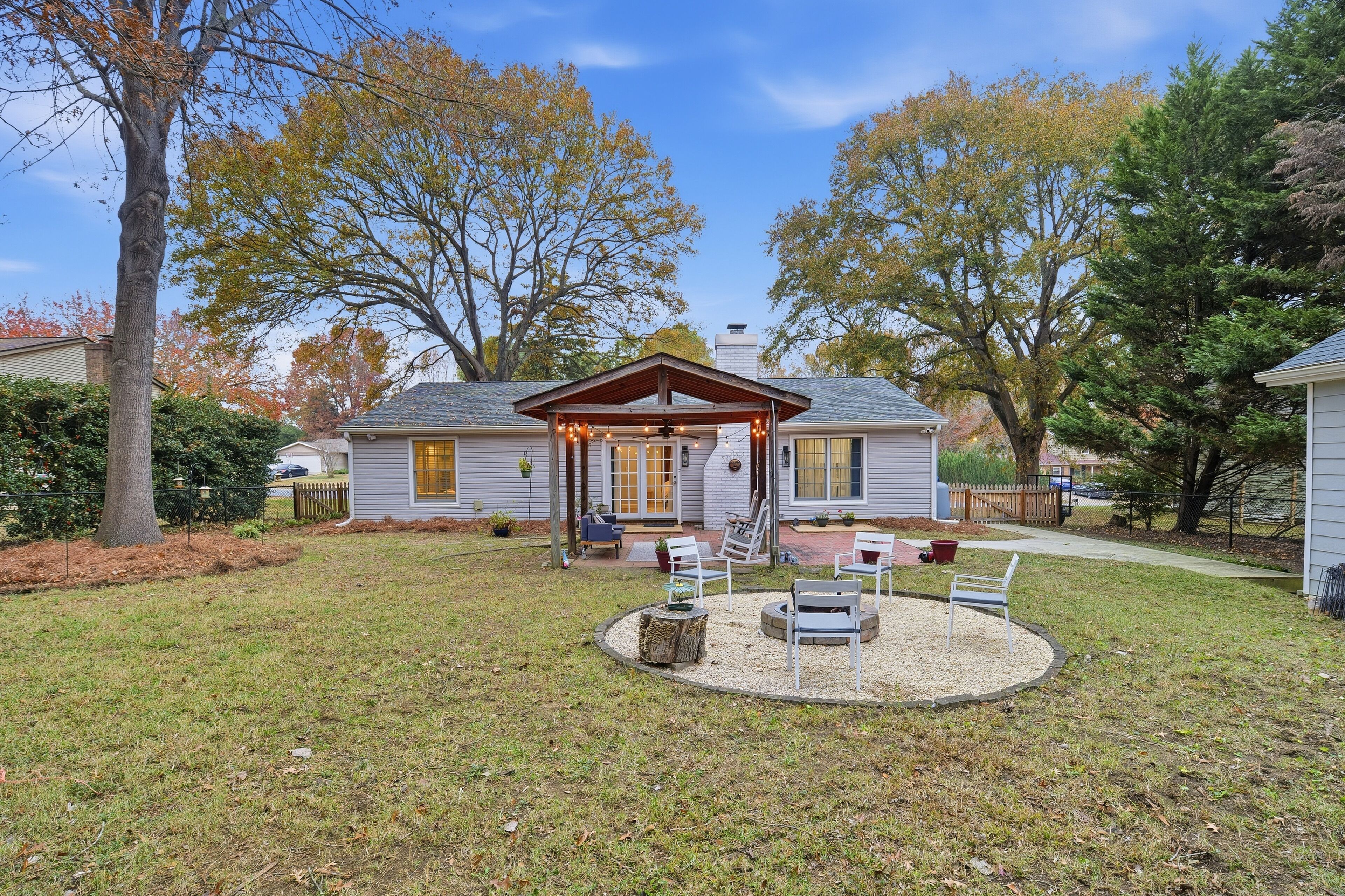 A house with a covered porch, a lawn, and trees in the background.