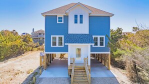 A two-story house with a front porch and a wooden staircase leading to the door. - Oceanside, Dog Friendly Home with Private Pool and Hot Tub (Salvo)