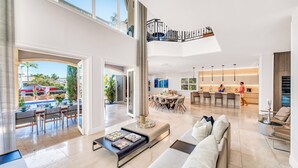 A spacious living area with a high ceiling, a dining area, and a kitchen. - Waterfront | Heated Pool | Canal View & Access | Paloma Key | VlLLAS (Fort Lauderdale)