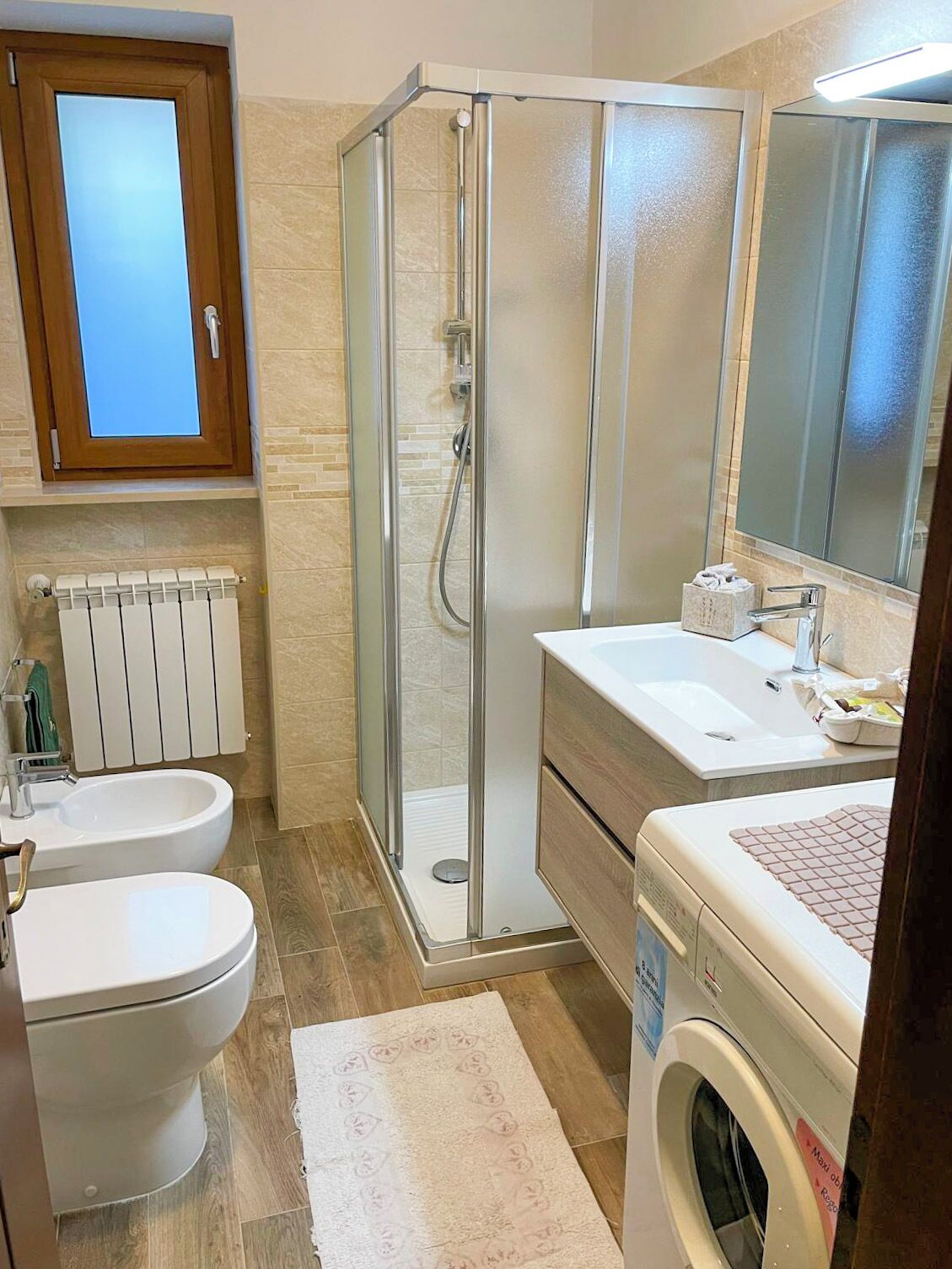 Une salle de bain avec une douche à parois de verre, des toilettes, un lavabo et un lave-linge.