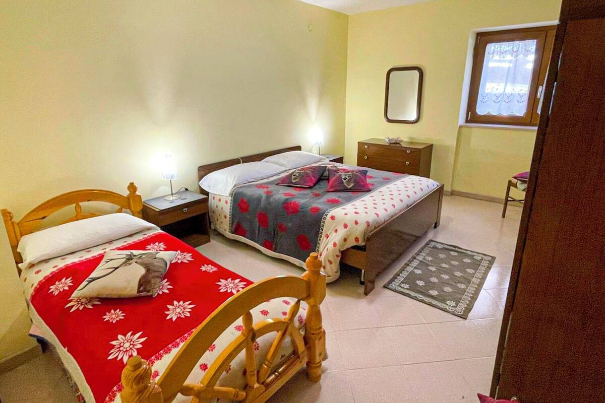 A bedroom with two beds, a nightstand, a dresser, a mirror, and a window.