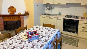 A kitchen with white cabinets, a gas stove, and a microwave. There is a table with a plaid tablecloth and a box with a red ribbon. - Casa Vacanze - Villa Stefania (Pescocostanzo)