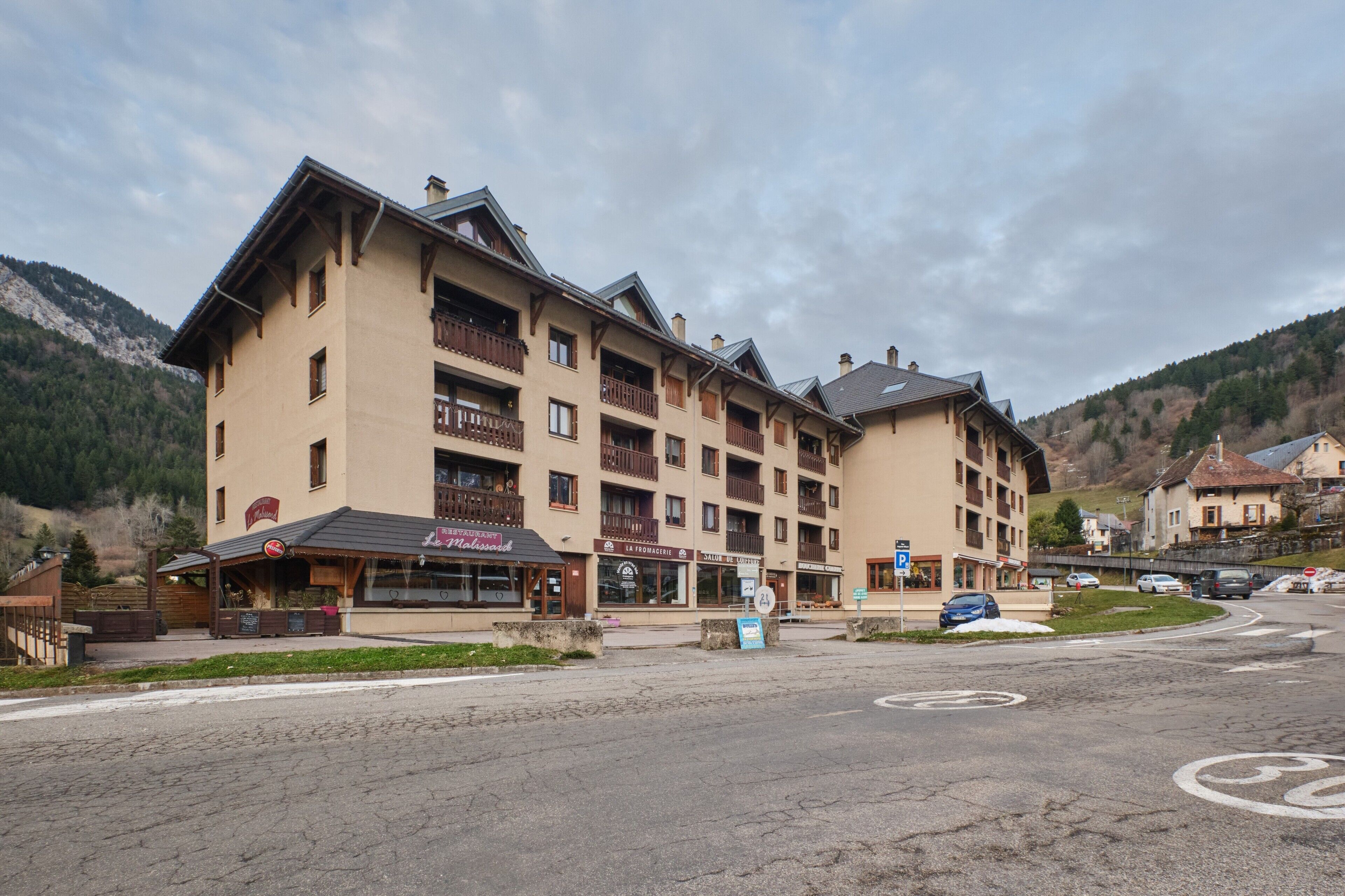 Een hotel met meerdere verdiepingen, voorzien van balkons, een restaurant en een parkeerplaats.
