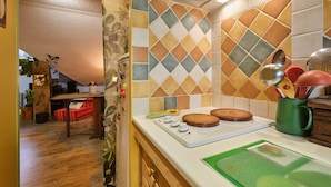 Een keuken met een betegelde spatwand, houten kastjes, een aanrecht en een groen snijplank.