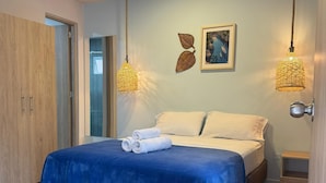 Un dormitorio moderno con cama, armario de madera y dos lámparas colgantes.