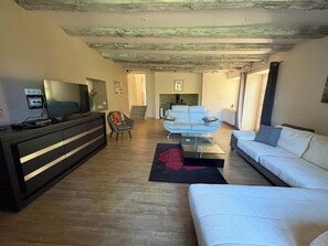 Una sala de estar moderna con un sofá, una mesa de centro y un televisor. Se ve una escalera que conduce a otra habitación.