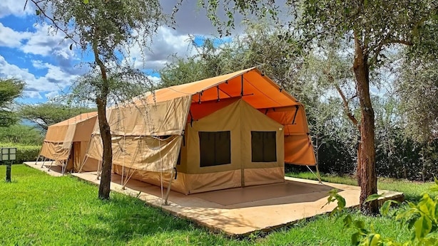 A single tent with a canvas exterior and a solid base, surrounded by trees and grass. - Northgate Resort Isiolo (Isiolo)
