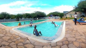 A swimming pool area with multiple pools, stone flooring, and a small building in the background. - Northgate Resort Isiolo (Isiolo)