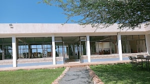 A building with a covered patio area, large windows, and a gravel pathway leading to the entrance. - Northgate Resort Isiolo (Isiolo)