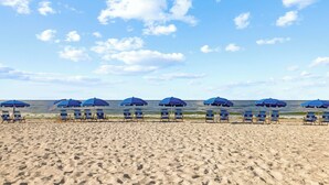 Une plage bordée de rangées de parasols bleus et de chaises de plage.