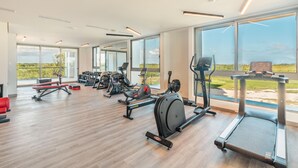 A modern gym with various exercise equipment, large windows, and a wooden floor. - 7 Mares E2 in Punta Cana (Punta Cana)