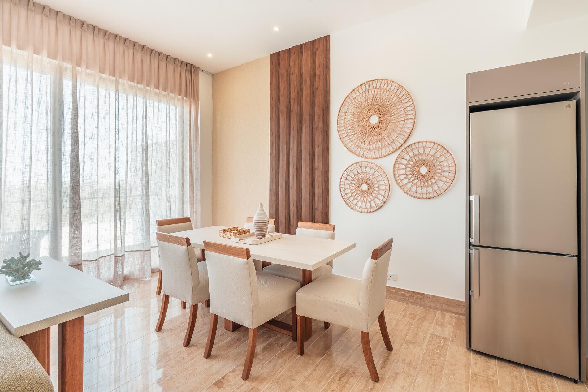 Une cuisine moderne équipée d’un réfrigérateur en acier inoxydable, d’une table à manger avec six chaises et de trois éléments décoratifs fixés au mur.