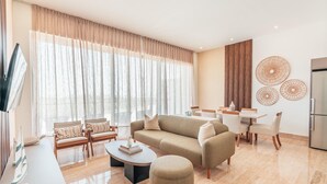 A modern living room with a sofa, chairs, a coffee table, and a dining area with a table and chairs. - 7 Mares E2 in Punta Cana (Punta Cana)