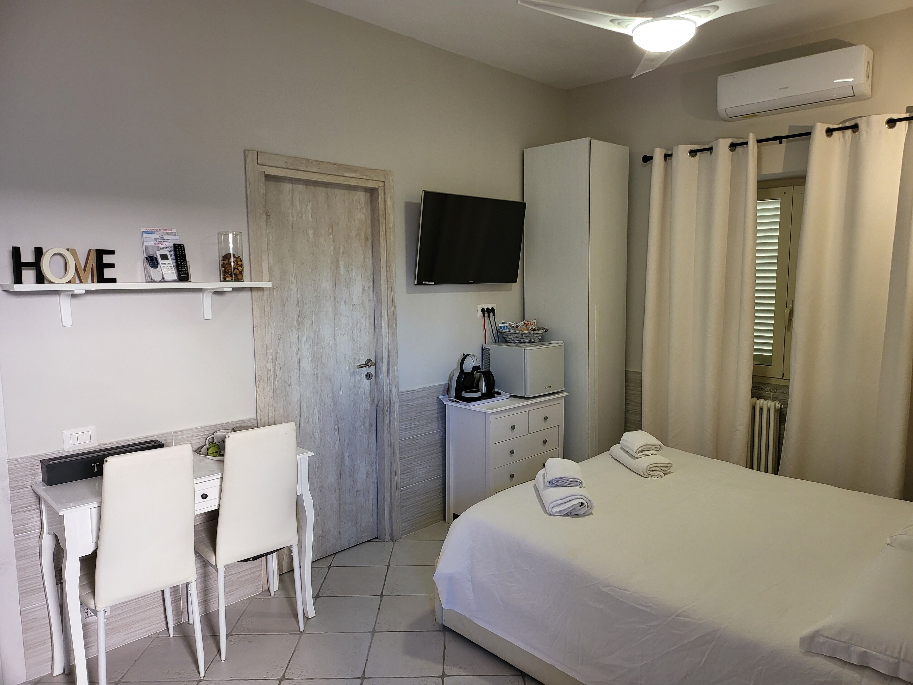 Une chambre d’hôtel comprenant un lit, un bureau avec une chaise, une télévision, une armoire et un espace douche.