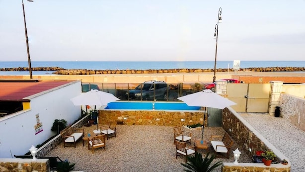 A rooftop patio with a pool, outdoor seating, and a view of the sea. - ALBACHIARA GUEST HOUSE (Fiumicino)