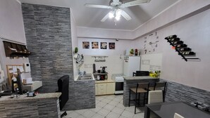 A modern kitchen with a dining area, a built-in stove, and a ceiling fan. - ALBACHIARA GUEST HOUSE (Fiumicino)