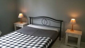 Una cama con un edredón a cuadros, dos mesitas de noche con lámparas y un cabecero.