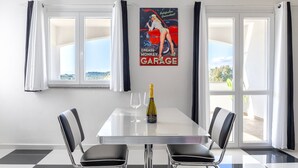 Ein Essbereich mit Tisch, Stühlen, einer Champagnerflasche und einem Vintage-Autoposter an der Wand.