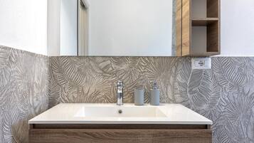 A bathroom with a white sink, wooden vanity, and a mirror above it.