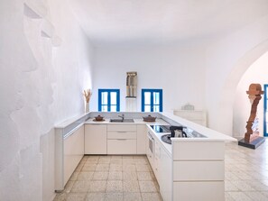 A modern kitchen with white cabinetry, a central island, and a blue door in the background.