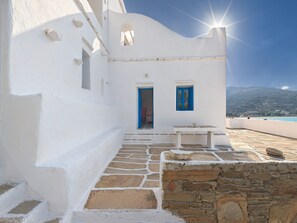 A white building with a stone staircase leading to a door with a blue frame.