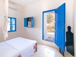 A room with a bed, a wardrobe, and a window with an open door leading outside.