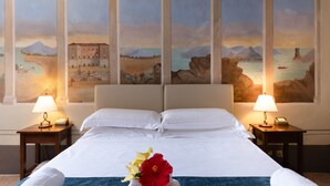 A hotel room with a large bed, two bedside tables with lamps, and a mural on the wall depicting a landscape with mountains and a body of water. - Hotel with swimming pool in Riparbella (Riparbella)