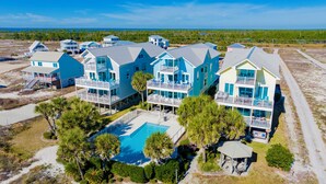 Een strandpand met meerdere twee verdiepingen tellende huizen, een zwembad en een tuinpaviljoen.