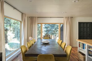 Uma sala de jantar com uma mesa comprida, cadeiras amarelas e uma estante de madeira.