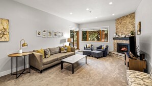 Un salon moderne avec un canapé, des fauteuils, une table basse et une cheminée.