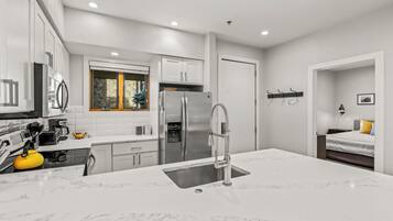 A modern kitchen with white cabinets, stainless steel appliances, and a marble countertop.
