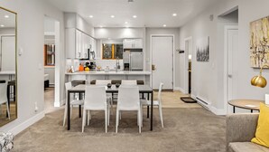 Une cuisine moderne avec des meubles blancs, un îlot central et un coin repas comprenant une table et des chaises.