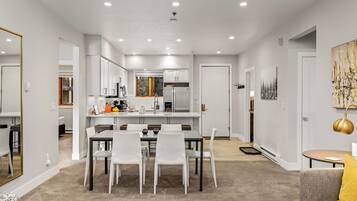 A modern kitchen with white cabinets, a central island, and a dining area with a table and chairs.
