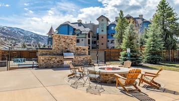 A patio with outdoor furniture and a fire pit, surrounded by a stone wall and a wooden fence.