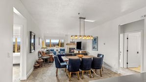 A spacious living area with a fireplace, a dining table with chairs, and a large window offering a view of the outdoors. - Base Area Condo | Steps to Ski | Pool and Hot Tub (Steamboat Springs)