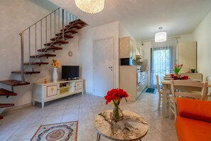 Uma sala de estar moderna com escada, área de jantar e cozinha.