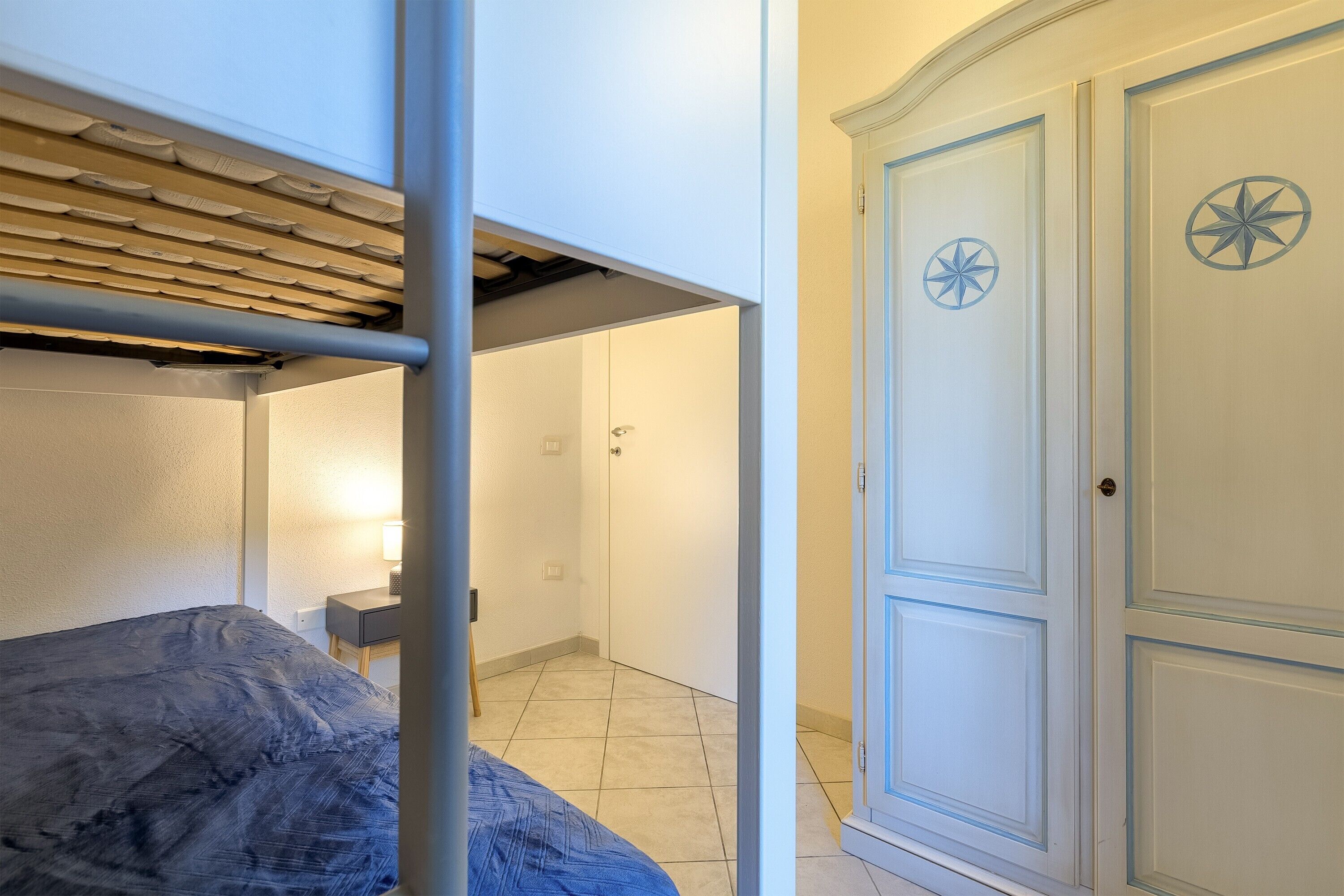 A bedroom with a bunk bed, a wardrobe with decorative panels, and a door with a star design.