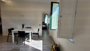 A modern interior with a dining area, a sofa, and a large window. - Sara luxury apartment 3 (Sorrento)