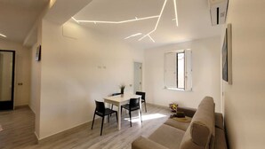A modern living space with a dining area, a sofa, and a window providing natural light. - Sara luxury apartment 3 (Sorrento)