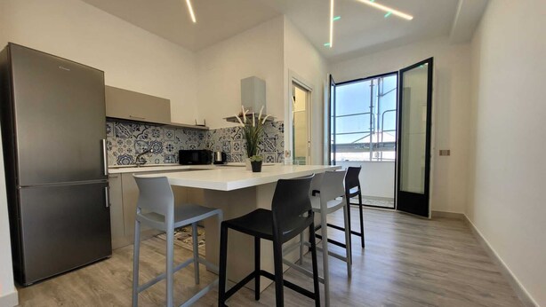 A modern kitchen with a central island, bar stools, and a large refrigerator. - Sara luxury apartment 3 (Sorrento)