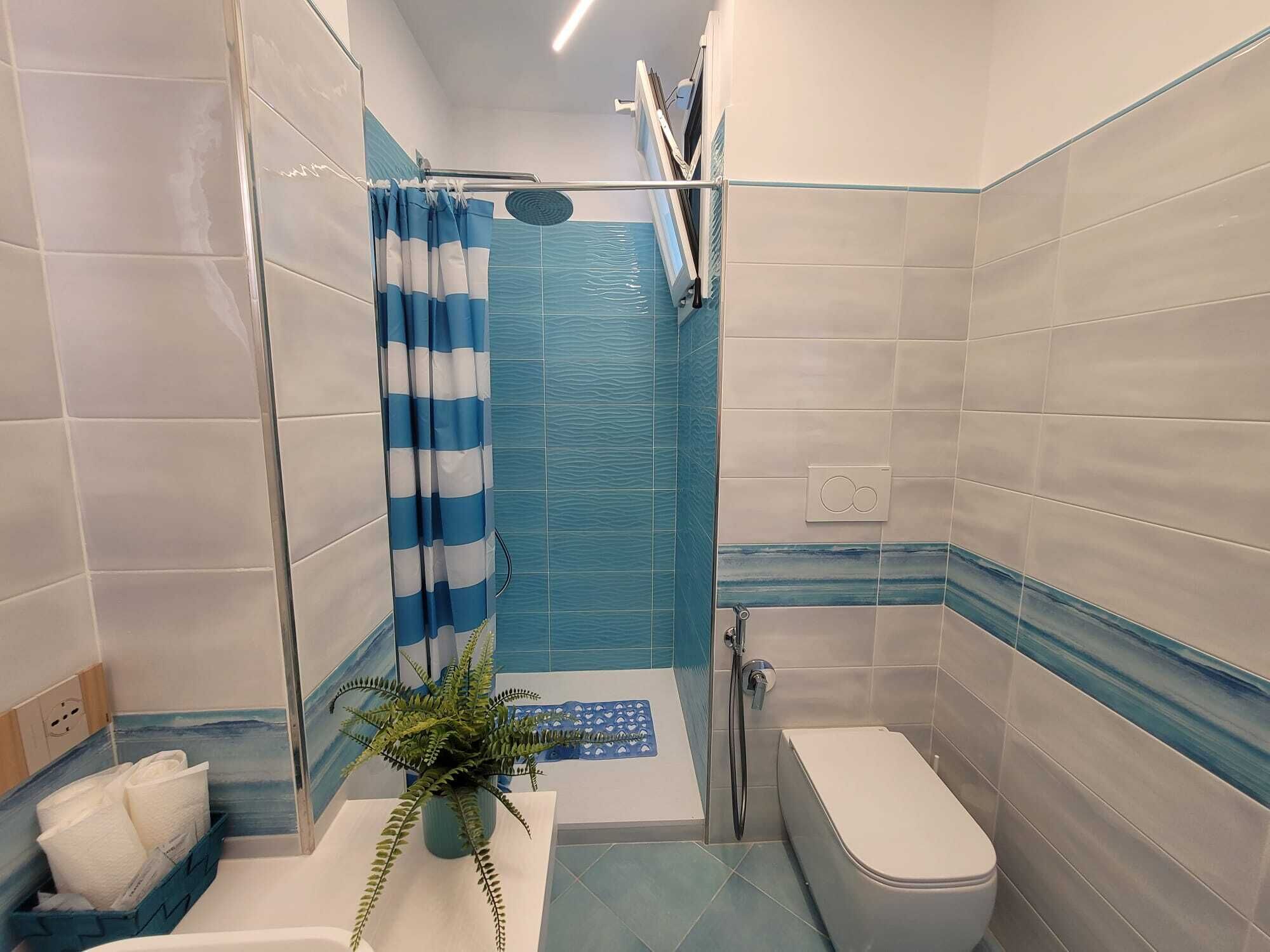 Et badeværelse med bruser, toilet og håndvask.