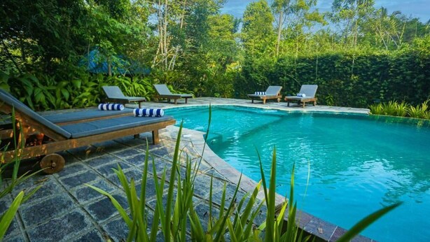 A swimming pool with lounge chairs and a stone deck. - Deluxe Double Room (Padinnoruwa)