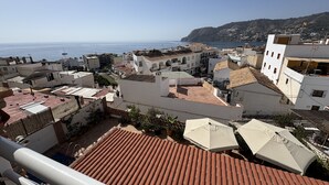 Eine Küstenstadt mit terrakottafarbenen Dächern, weißen Gebäuden und Blick auf das Meer.