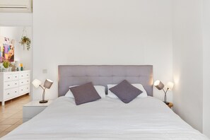 A neatly made bed with a grey headboard, two bedside lamps, and a white bedside table with a lamp. - Room 'Brise Mimosa' with Mountain View, Wi-Fi and Air Conditioning (Alhaurín el Grande)